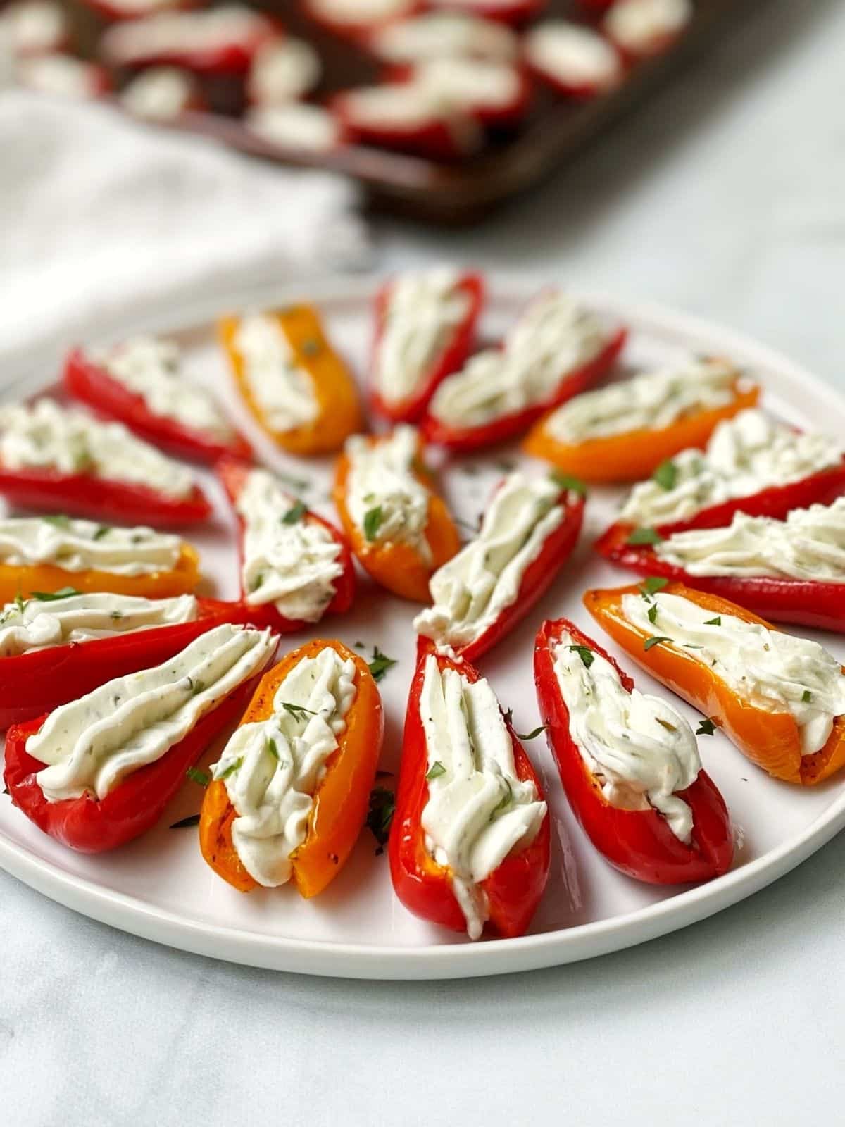 white plate of stuffed peppers with baking sheet in the background