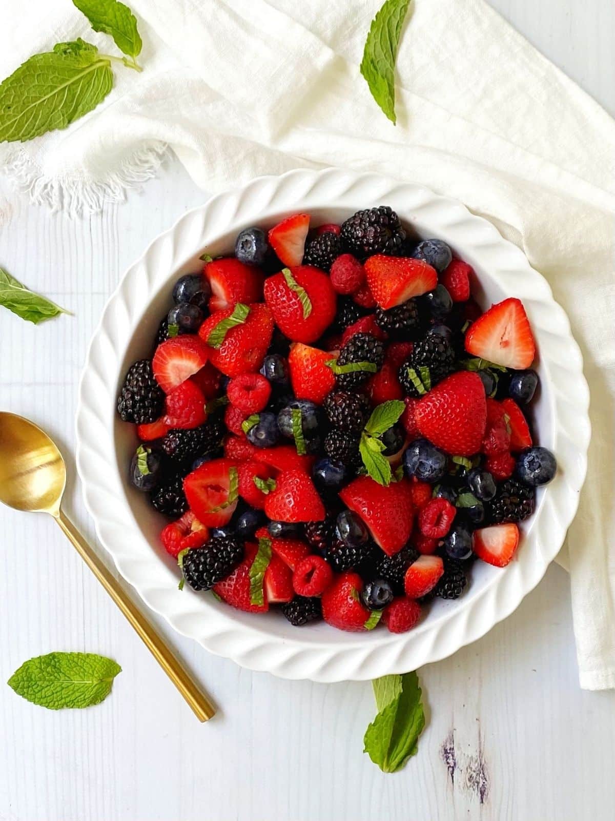 overhead shot of fruit salad in a white dish with serving spoon on the side