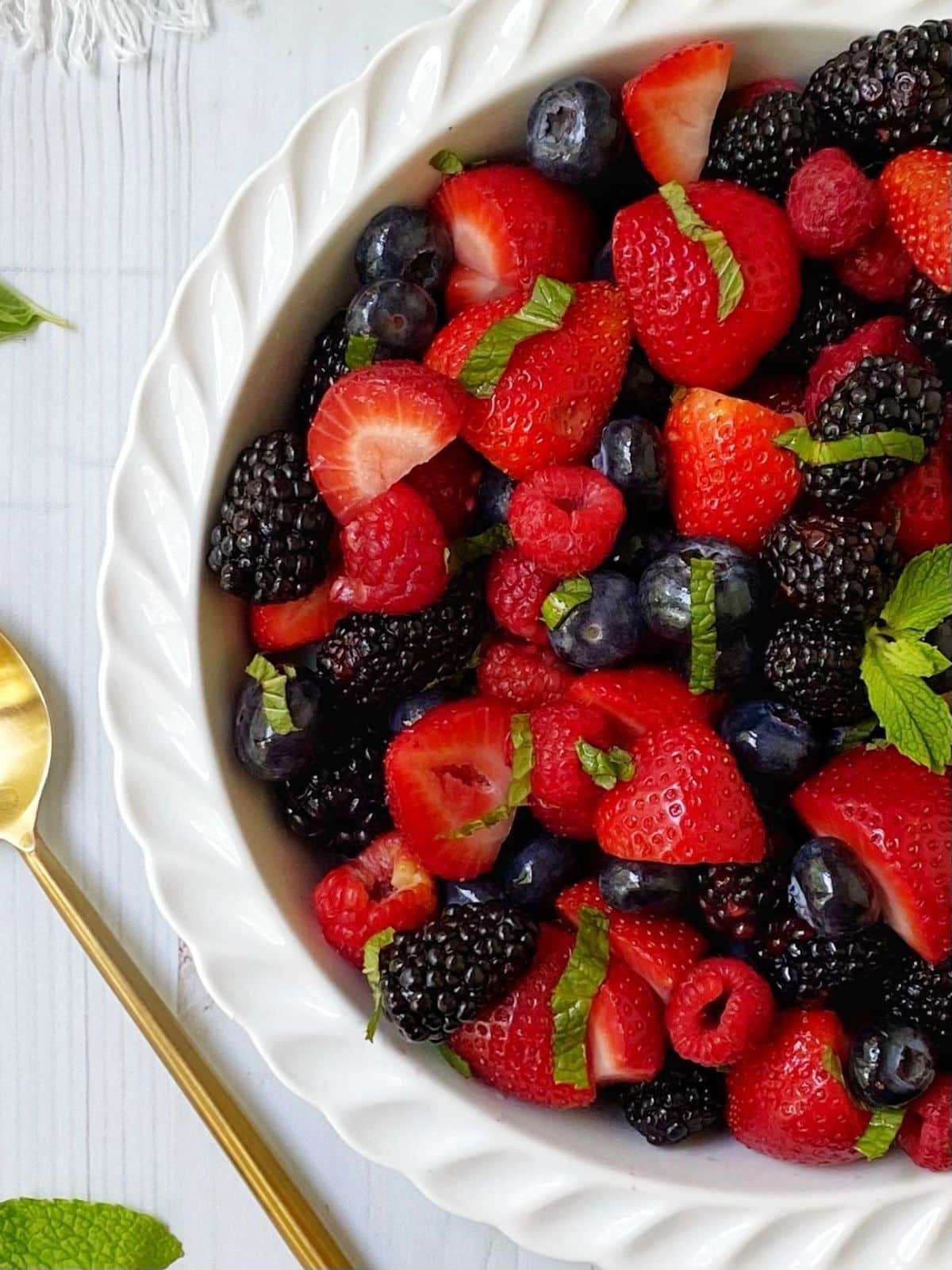 serving spoon laying next to white dish of fruit salad