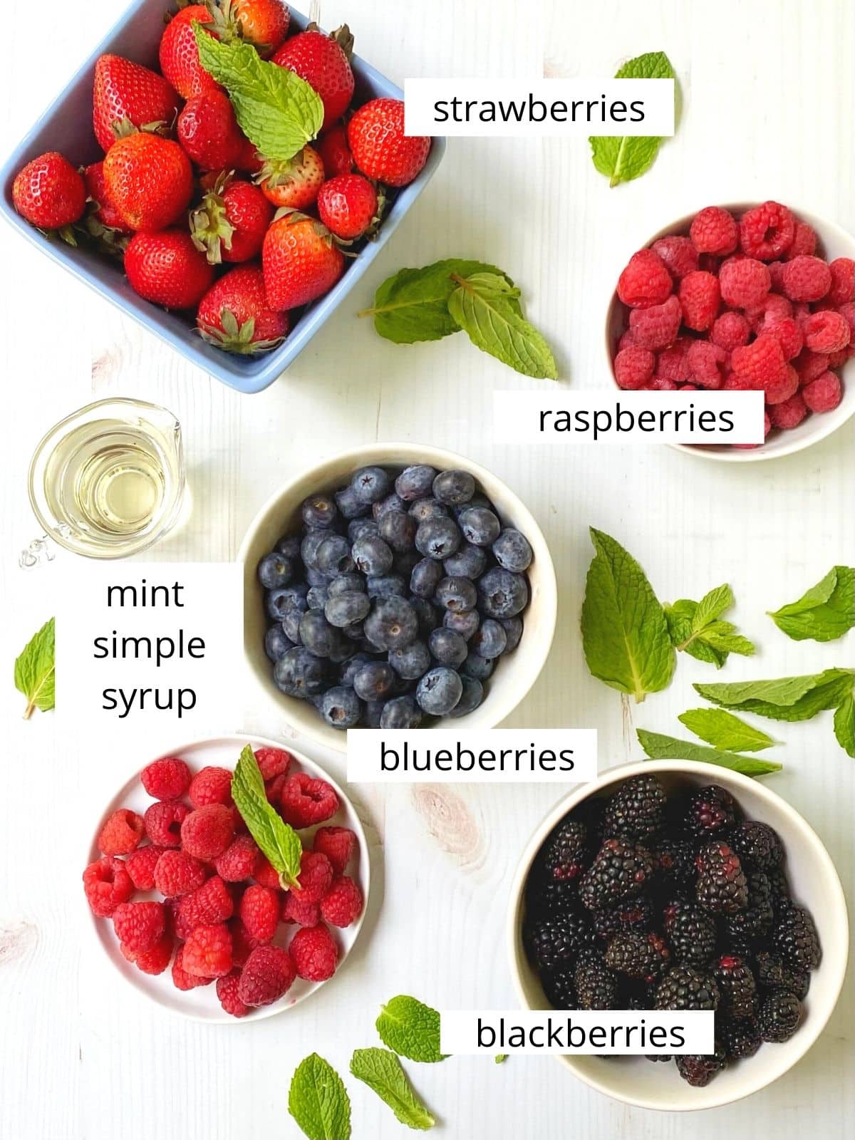 array of ingredients - strawberries, blueberries, raspberries, blackberries, mint simple syrup