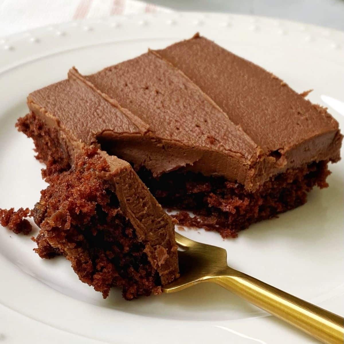 forkful of cake laying next to a piece of cake on a white plate