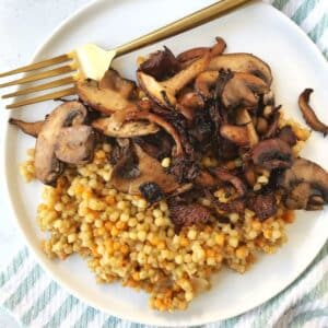 fork on a plate with cooked mushrooms and couscous