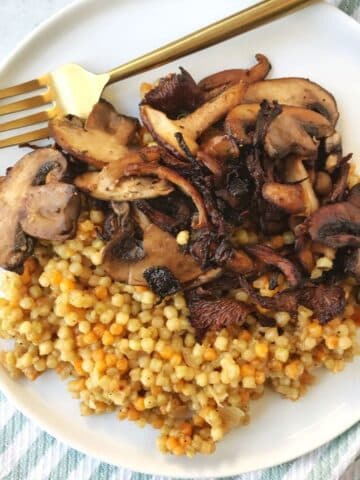 fork on a plate with cooked mushrooms and couscous