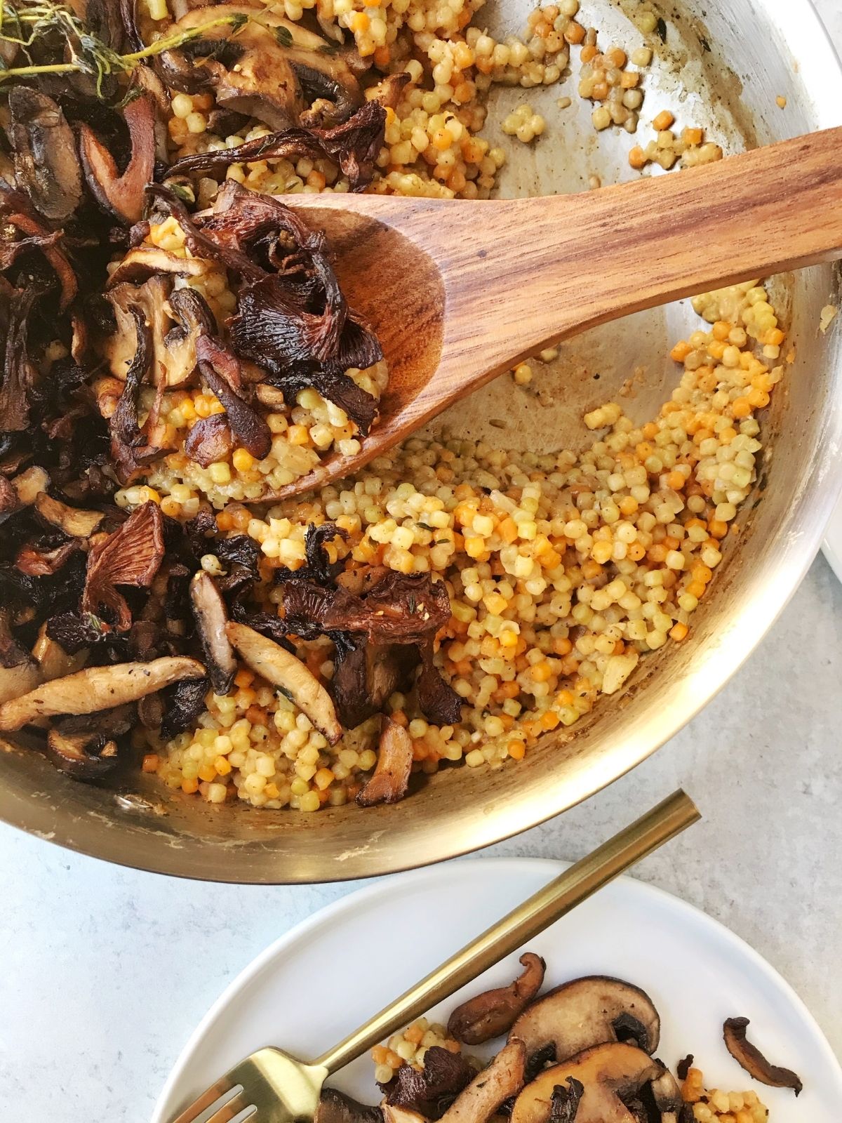 spoon in pan of couscous and mushrooms