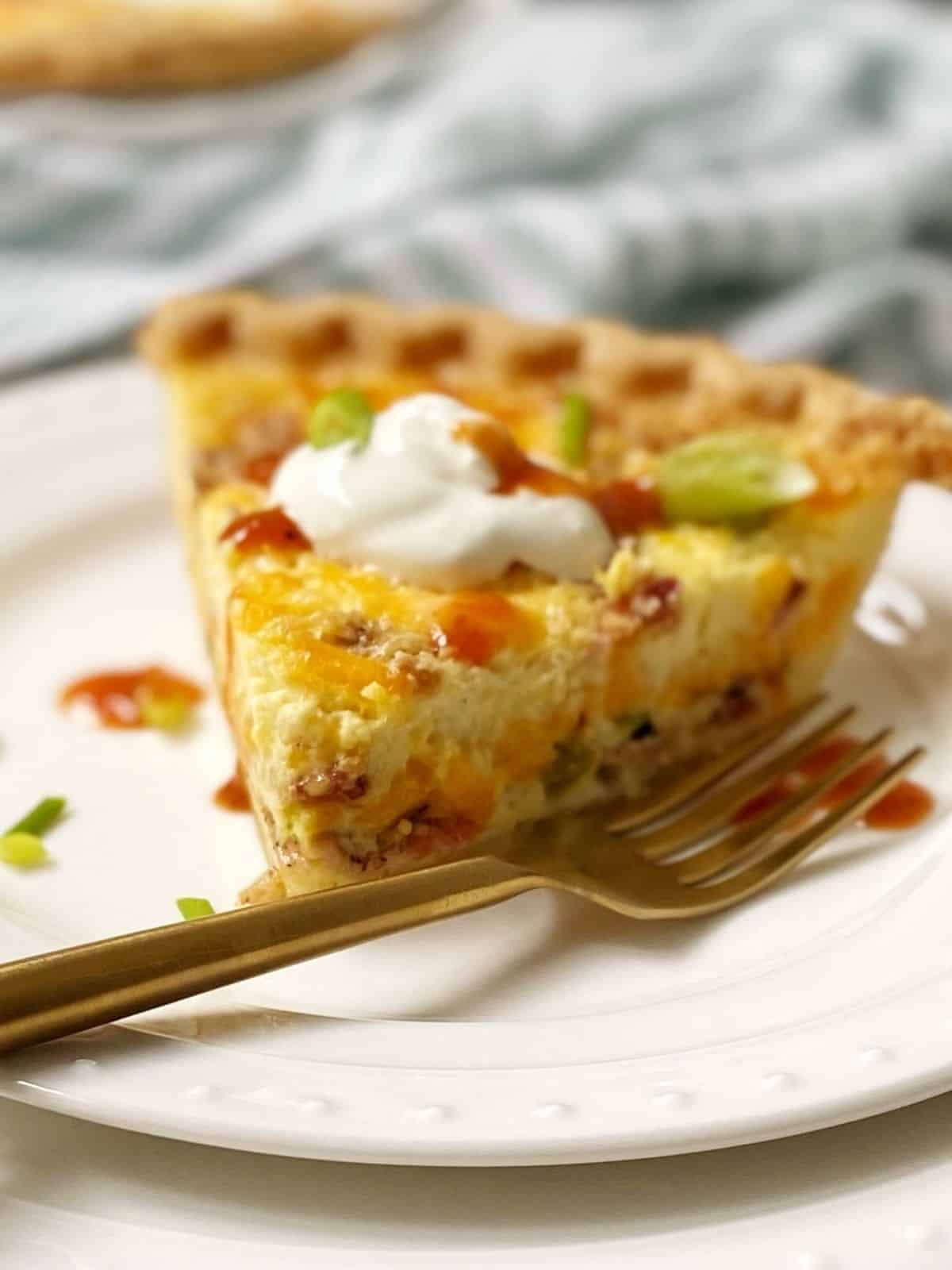 side view of slice of quiche on a white plate.