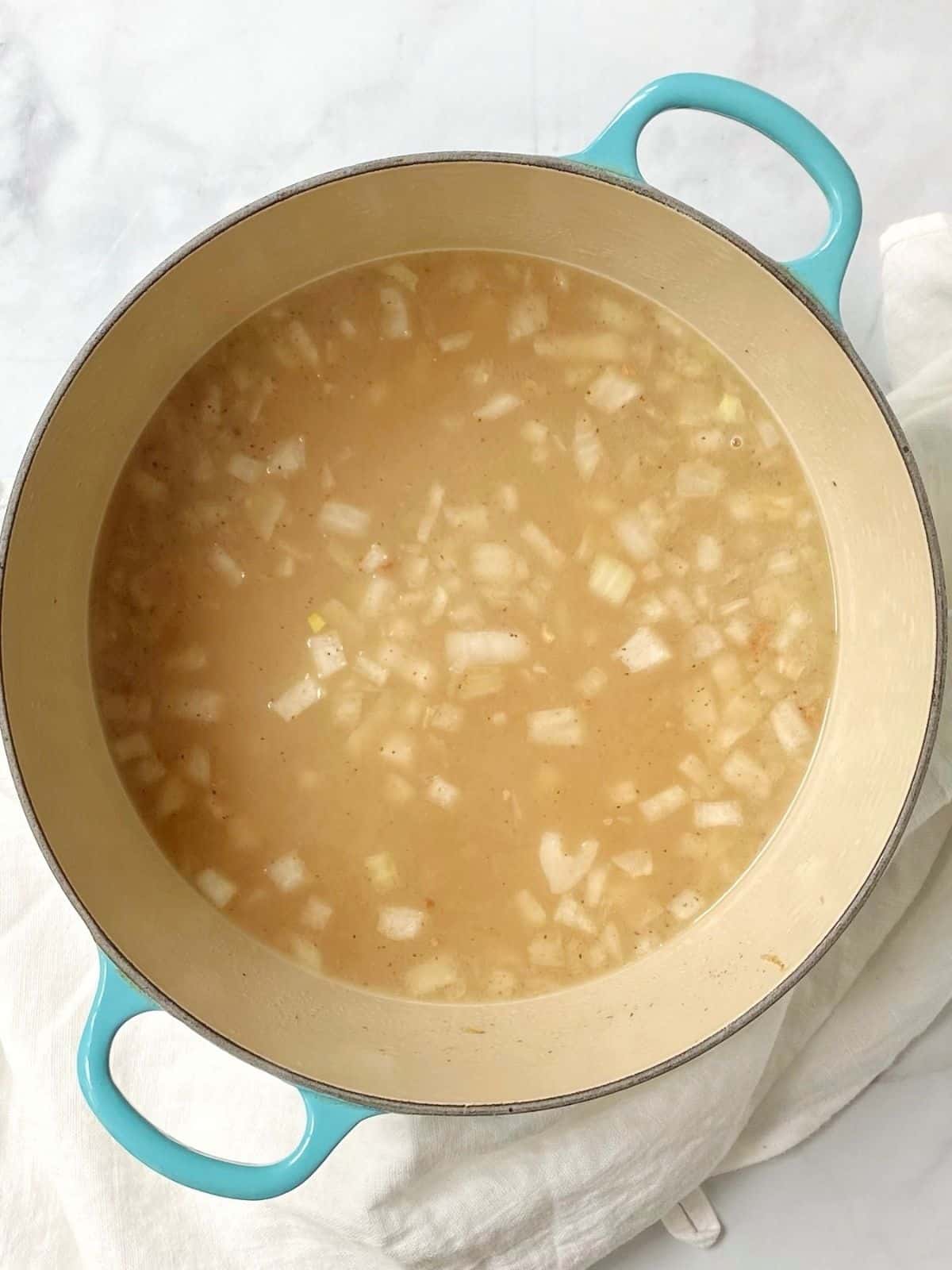 adding broth to potato gnocchi soup
