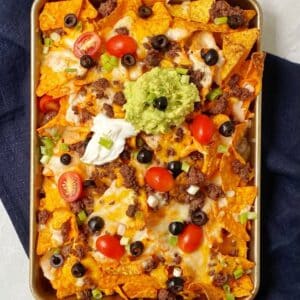 top down shot of nachos in pan with garnishes.
