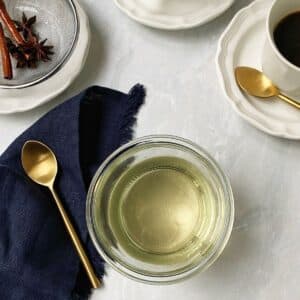 glass jar of simple syrup next to coffee cups