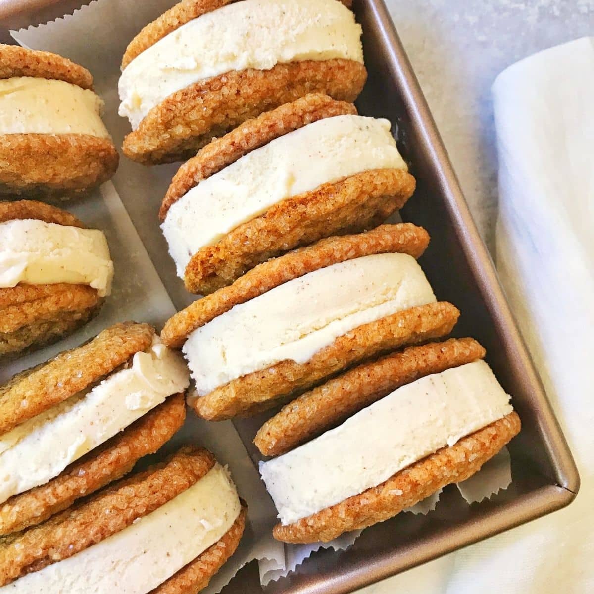 ice cream molasses cookie sandwiches lined up in a pan.