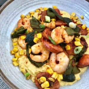 bowl of shrimp and andouille on top of corn puree.