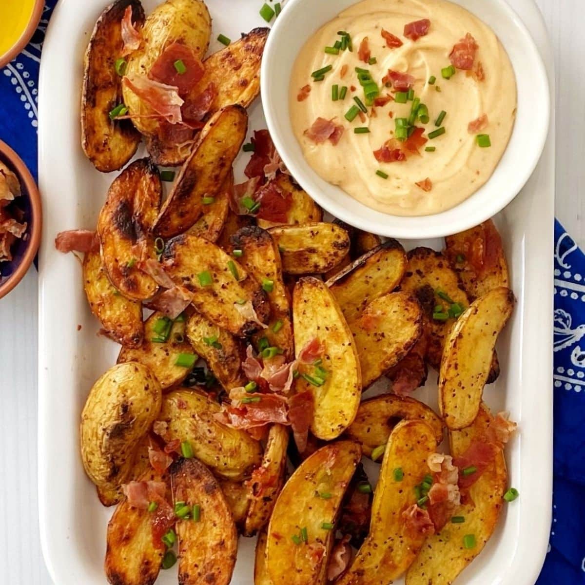 white platter of potatoes with dipping sauce.