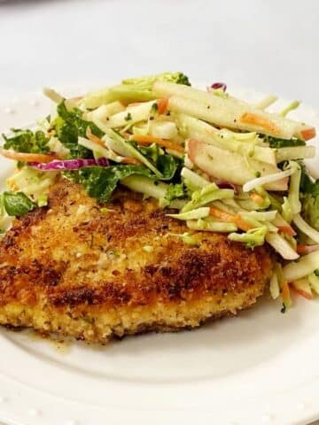 chicken cutlet topped with slaw on a plate.