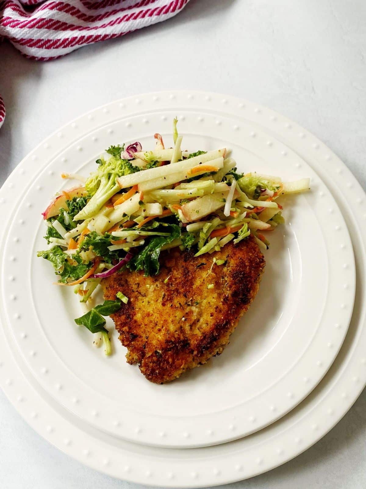Chicken topped with slaw on a plate.