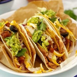 close up side view of 3 tacos on a plate.