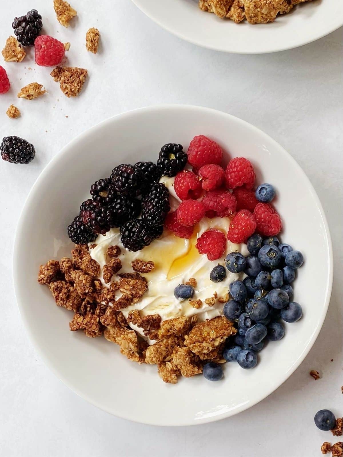 white bowl of berries, granola and yogurt.