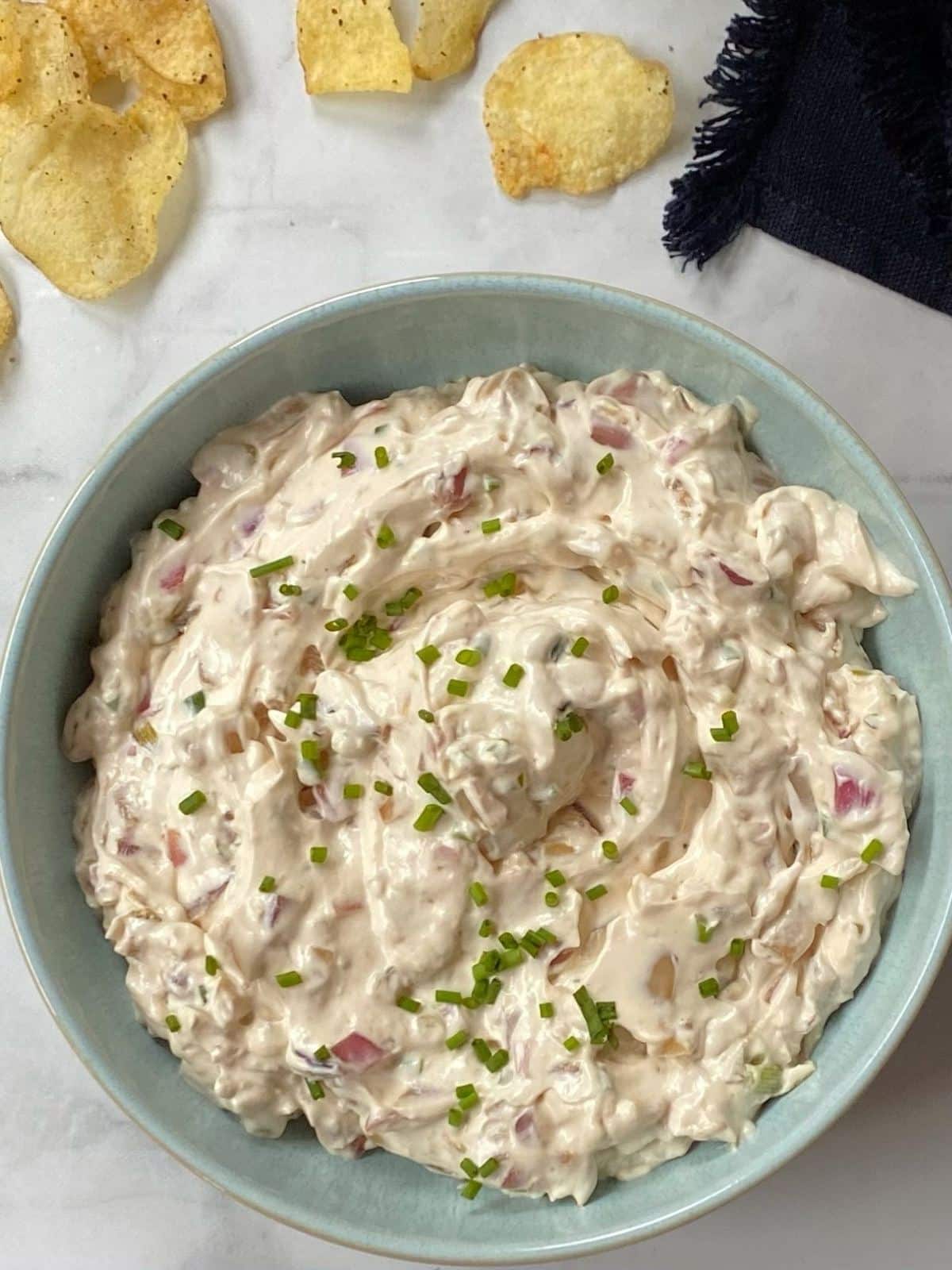 close up of bowl of dip next to some chips.