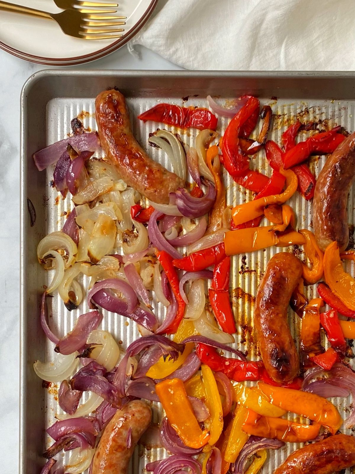 cooked sausage, peppers, onions on baking sheet.