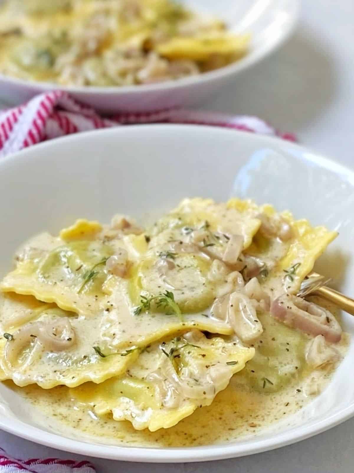 close up of ravioli and sauce in white bowls.