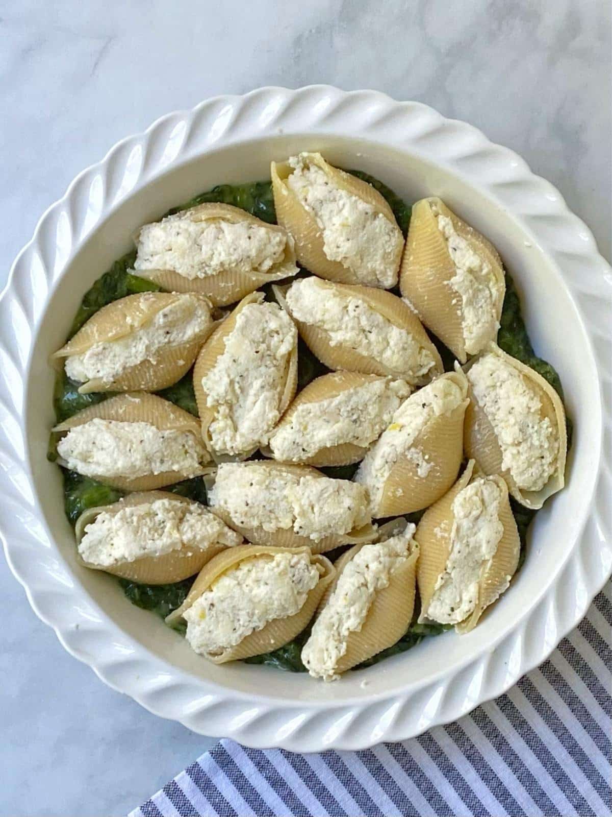 stuffed shells arranged over spinach in baking dish.