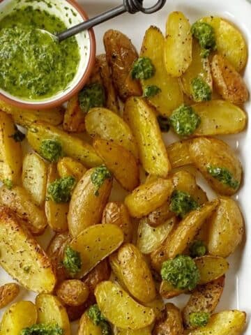 platter of roasted potatoes with herb sauce.