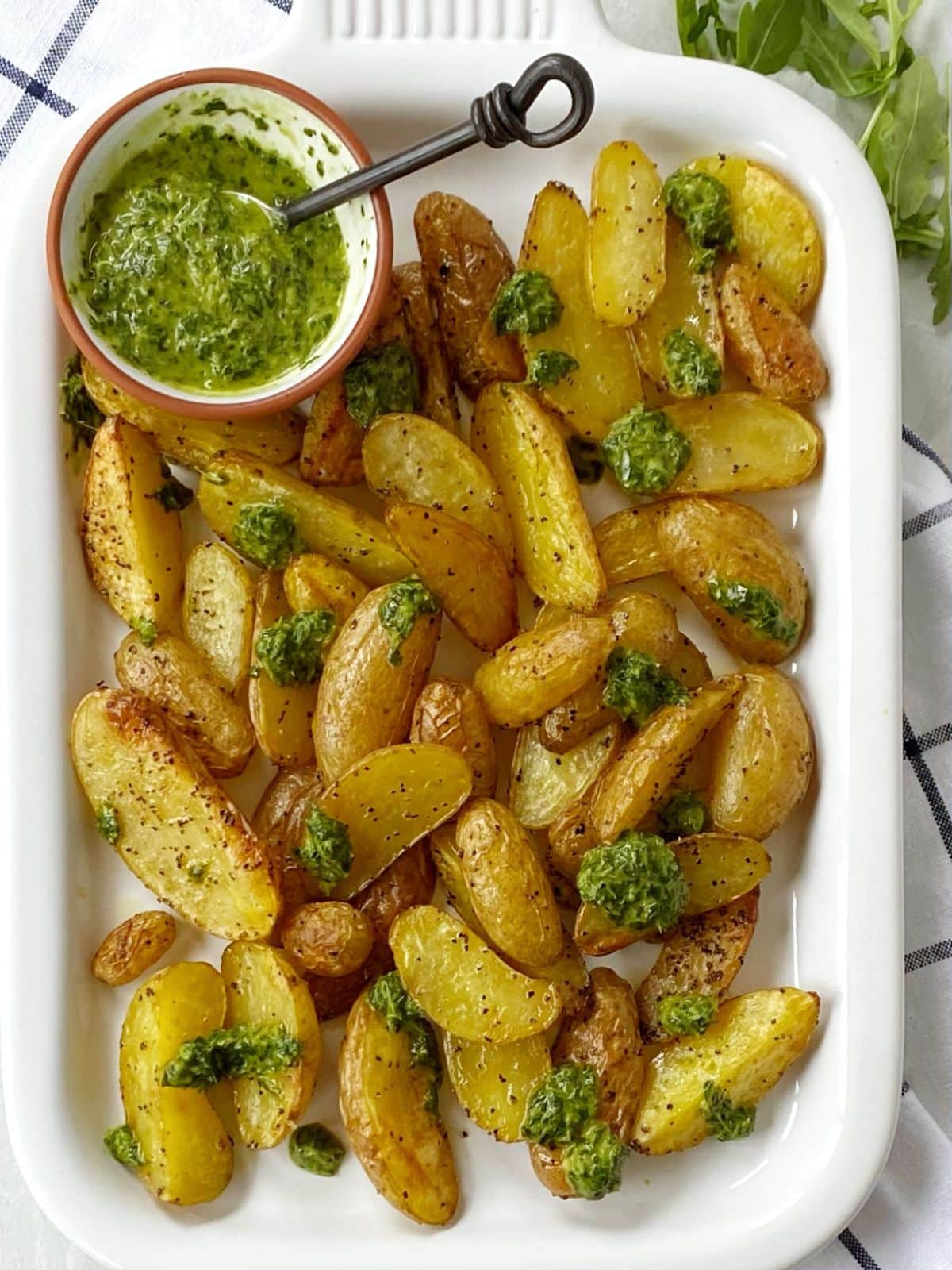 white platter with potatoes and herb sauce.