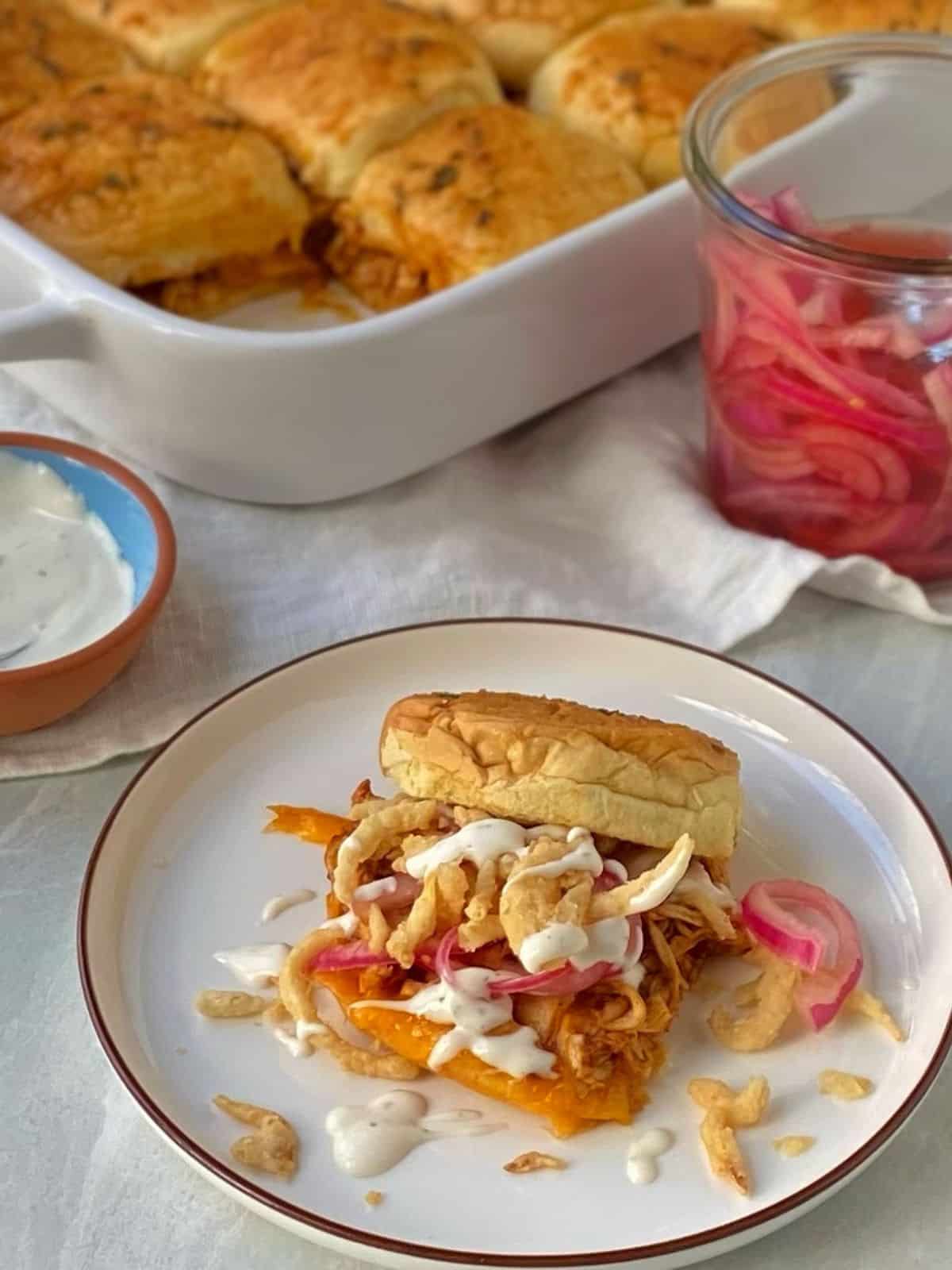 chicken slider on a plate with casserole dish in background.