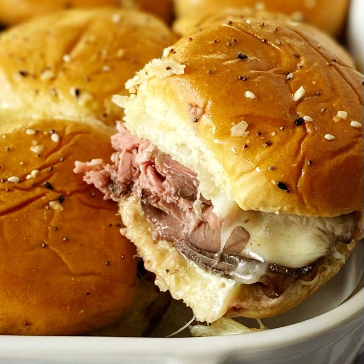 lifting horseradish roast beef slider out of baking dish.