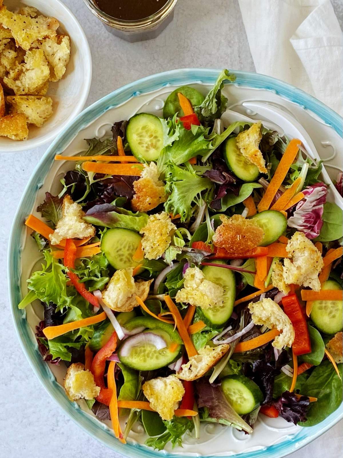 serving bowl of house salad with croutons and dressing on the side.