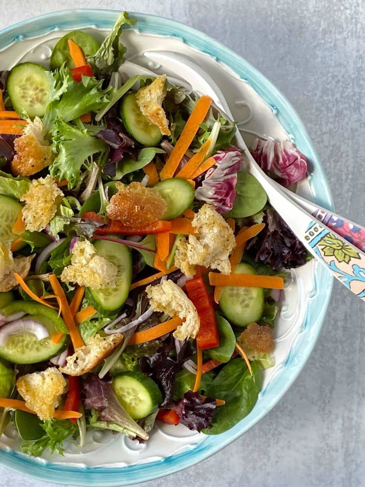 serving spoons in bowl of house salad.