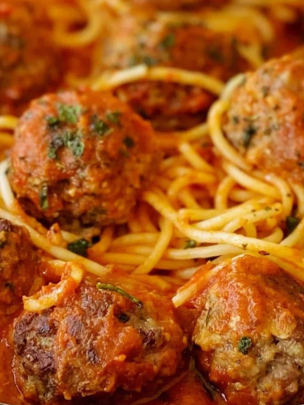 close up of meatballs with pasta and sauce.