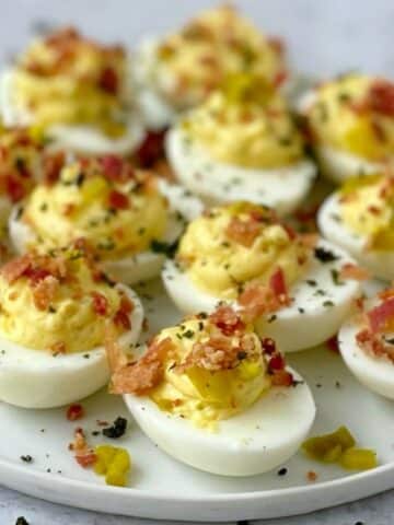 close up of deviled eggs on a white plate.