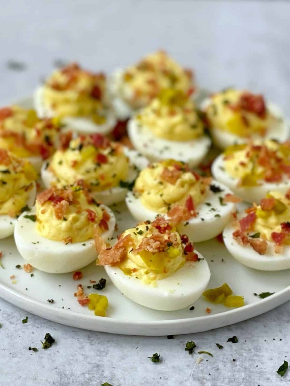 side view of garnished deviled eggs on a plate.