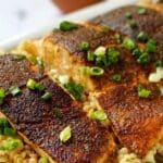 close up of salmon on a bed of couscous topped with scallion butter.
