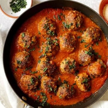 close up of skillet of Italian meatballs baked in pizza sauce.