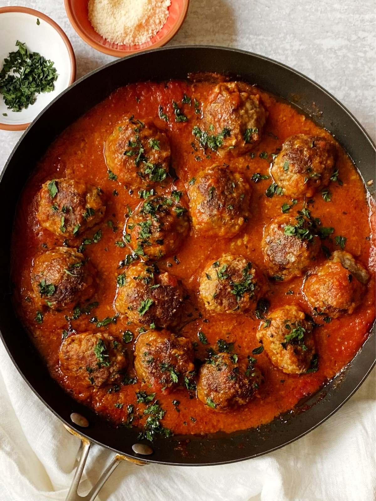 top down centered shot of skillet of Italian meatballs baked in sauce.