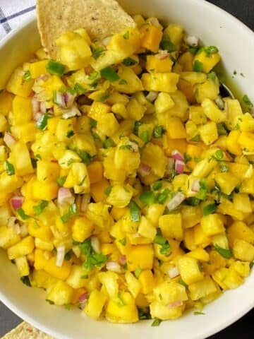 top down shot of mango pineapple salsa with tortilla chips on the side.