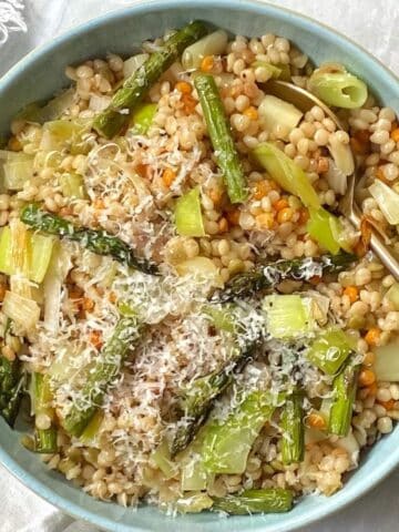 Bowl of brown butter couscous and veggies with a serving spoon.