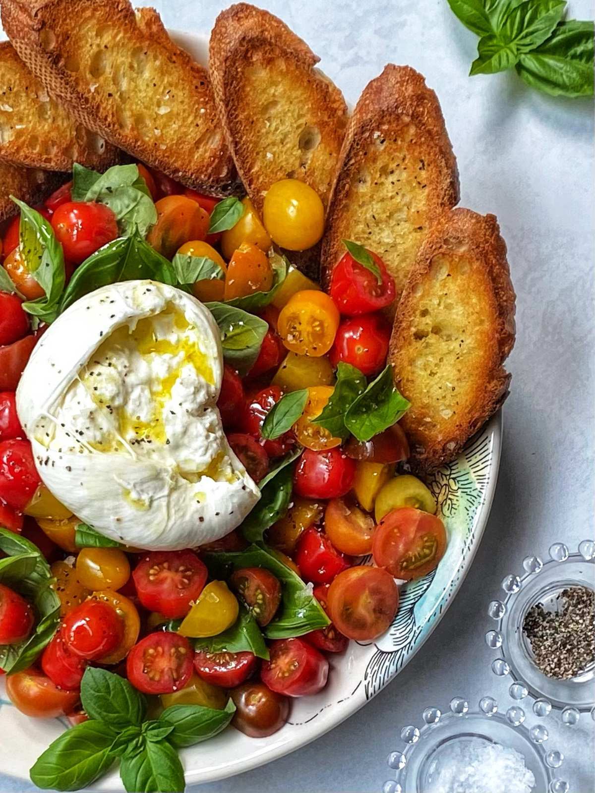 platter of caprese salad with burrata and crostini.