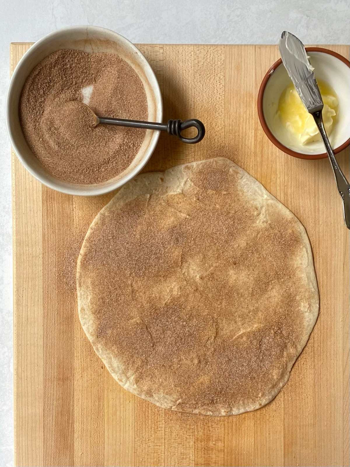 tortilla topped with butter and cinnamon sugar before moving it to the griddle.