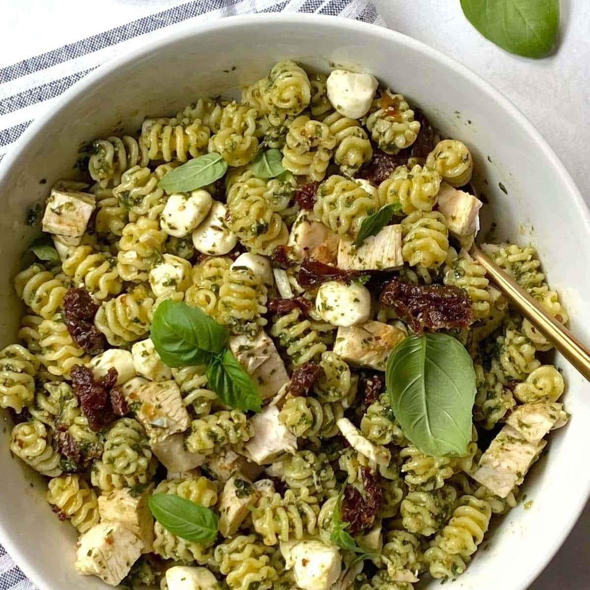 white serving bowl of chicken pesto pasta salad.