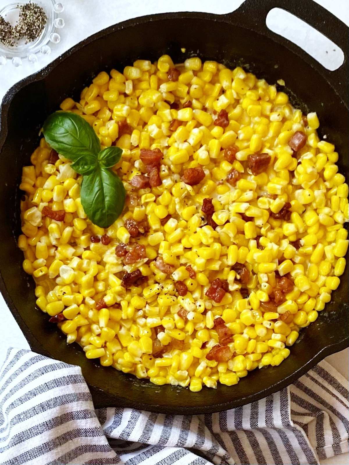top down shot of corn with pancetta in a cast iron skillet.