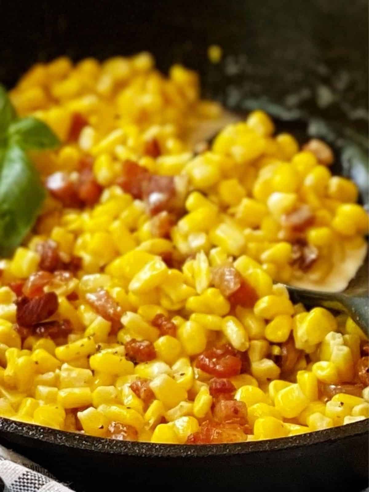 close up of cream corn and pancetta in a skillet.