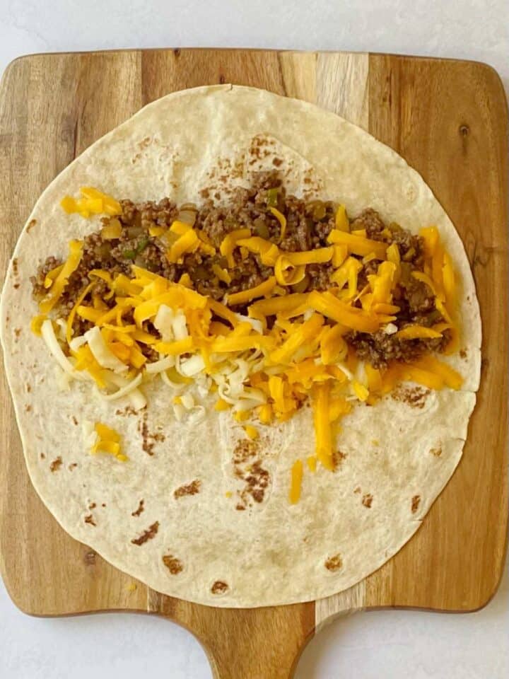filling tortillas with cheese and beef mixture.