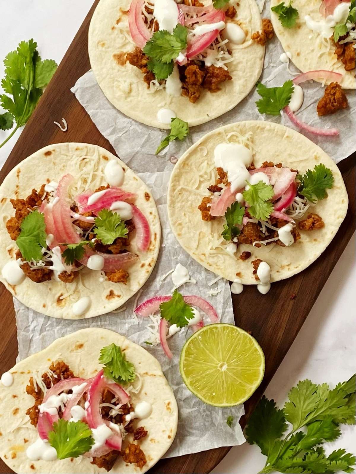 tortillas topped with chorizo, cheese, and garnishes on a serving platter.