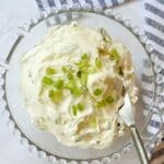 glass dish of scallion cream cheese with a spreader.