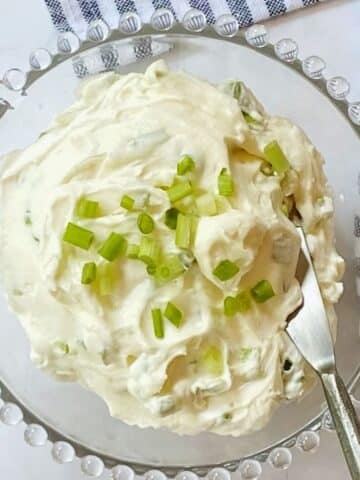 glass dish of scallion cream cheese with a spreader.