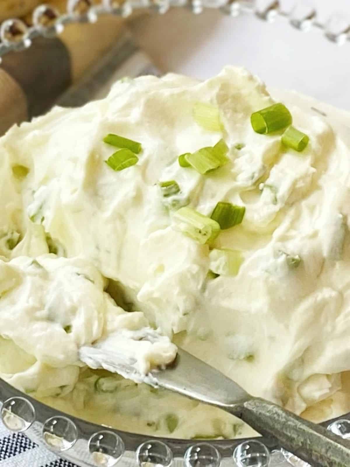 close up of scallion cream cheese in a serving dish.