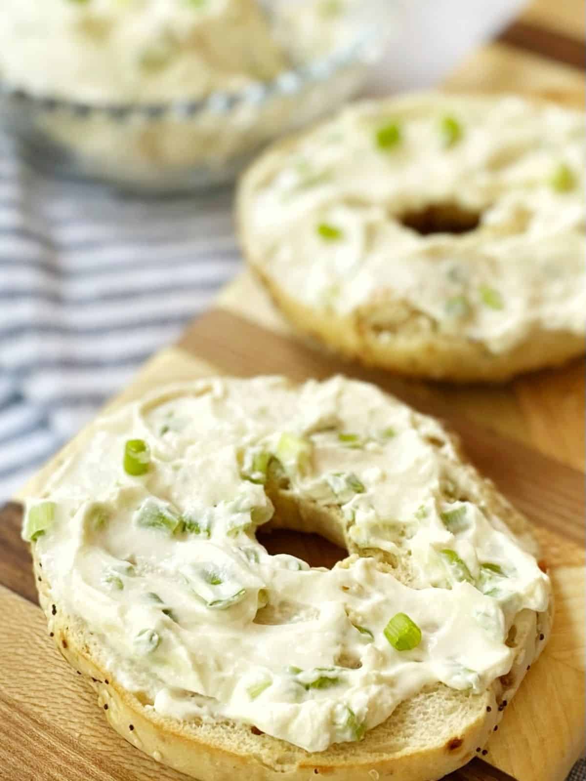cream cheese spread on bagels on a board.