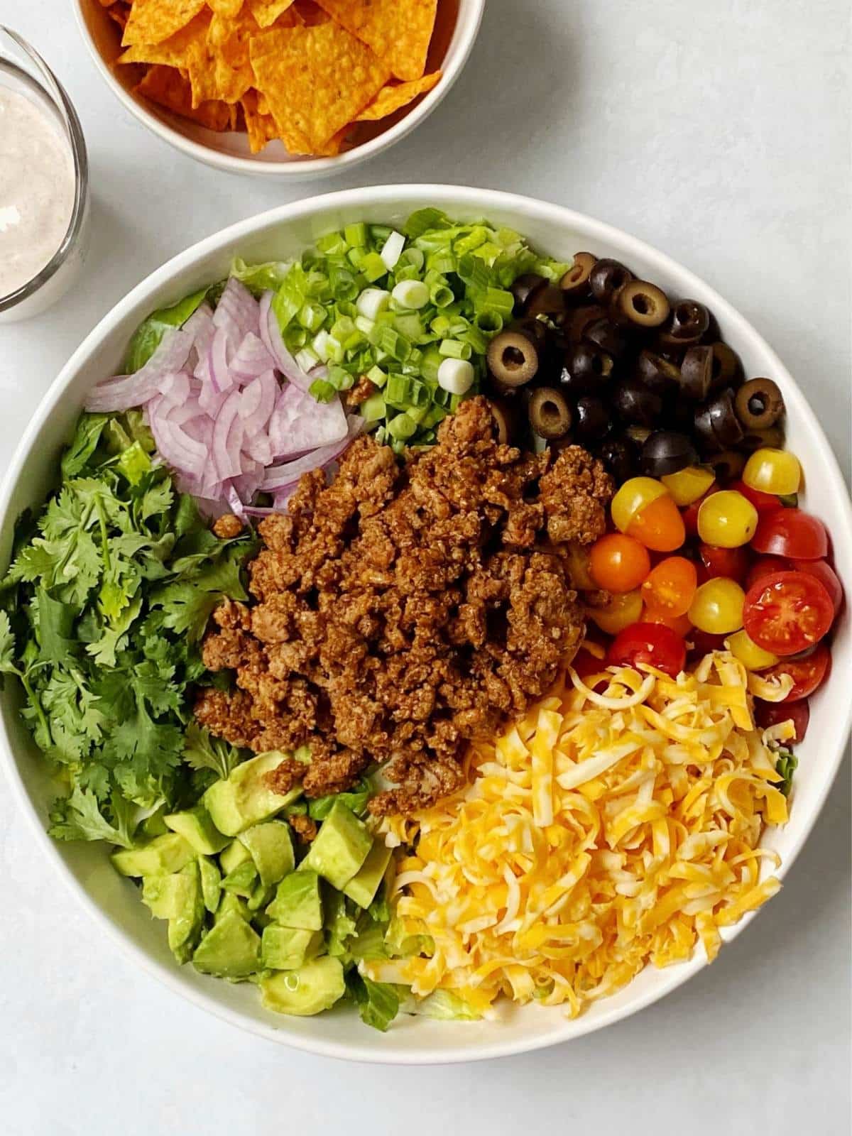 Serving bowl filled with lettuce and topped with the other ingredients in groupings.