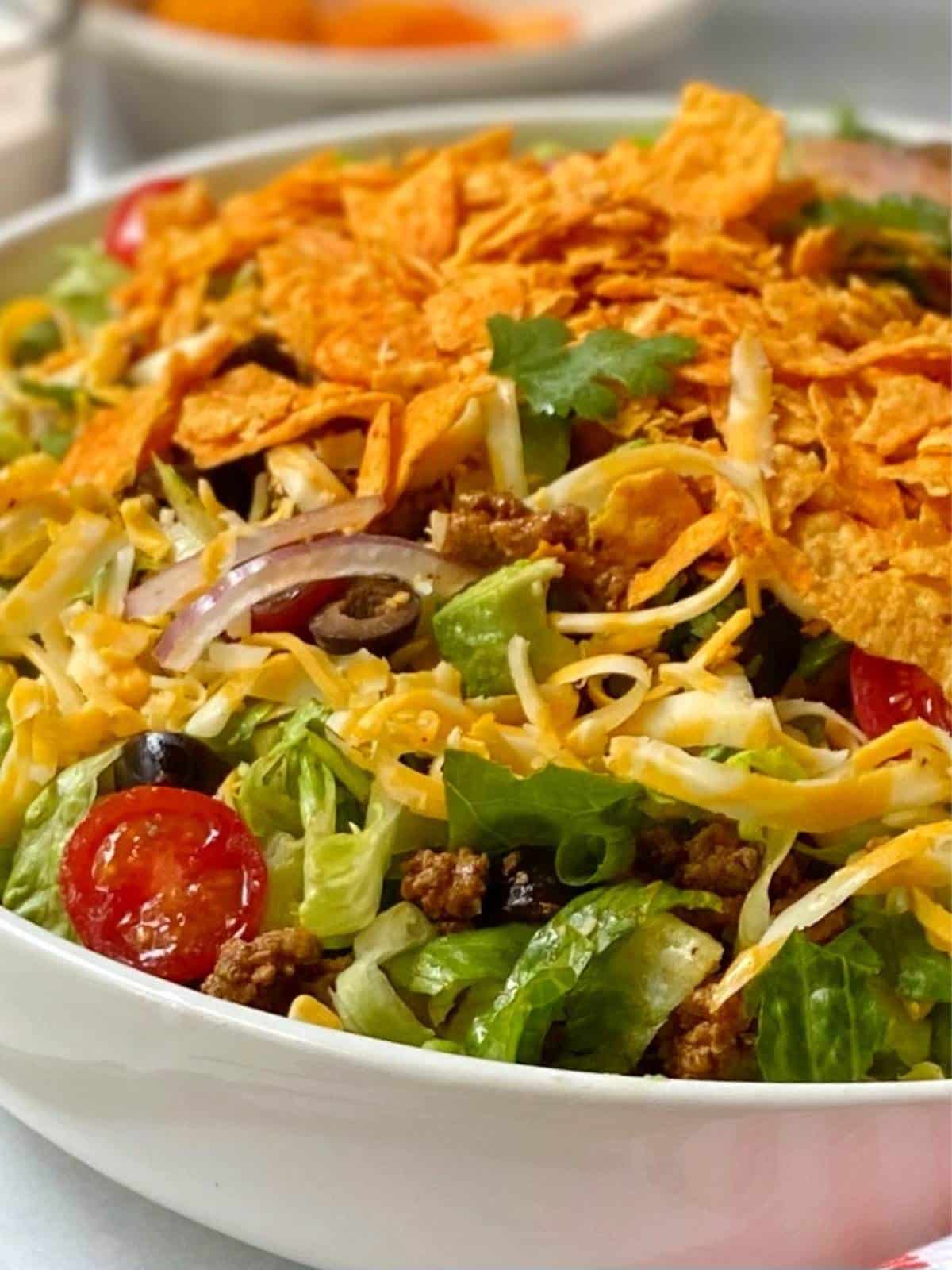 Close up of white serving bowl filled with Doritos taco salad.